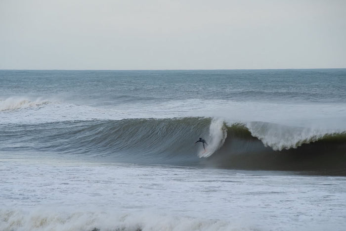 Surfer dropping into a hollow wave in Devon, photographed by Christian Jones.