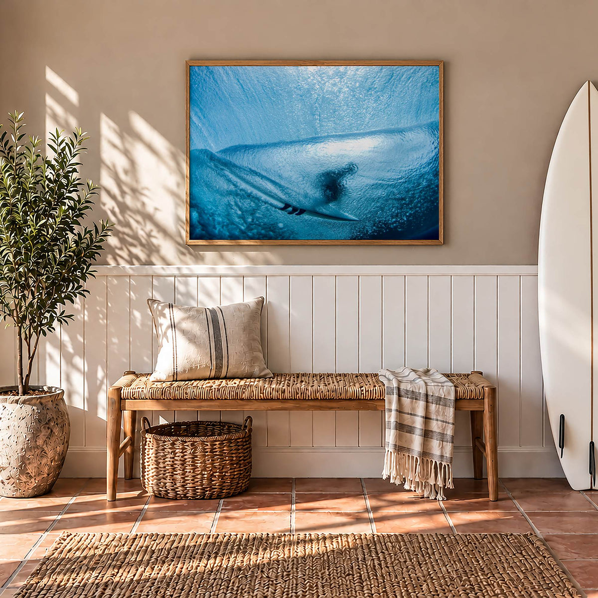 Aqua Cocoon surf photography print by Sean Davey framed in a hallway above a bench, beside a surfboard