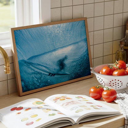 Aqua Cocoon surf photography print by Sean Davey framed and leaning on a kitchen counter beside tomatoes and a cookbook