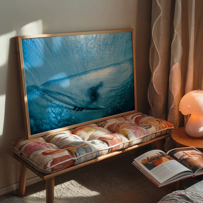 Aqua Cocoon surf photography print by Sean Davey framed and leaning on a cushioned bench beside a lamp