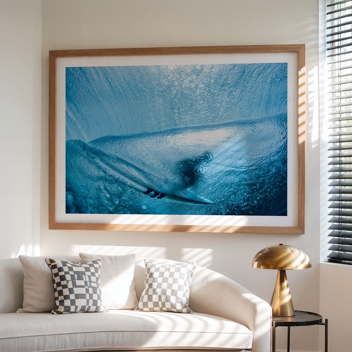Aqua Cocoon surf photography print with a white border by Sean Davey framed above a sofa beside a lamp