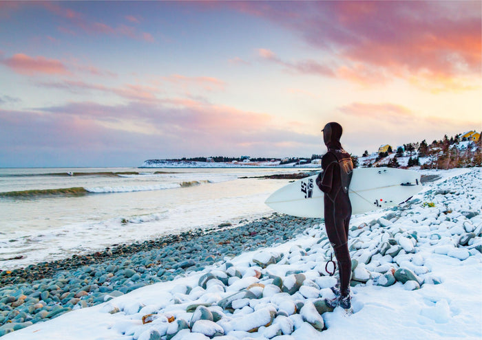 Chilled Vibes, a surfer on snow-covered rocks at sunrise in Lawrencetown, Nova Scotia, photographed by Adam Cornick