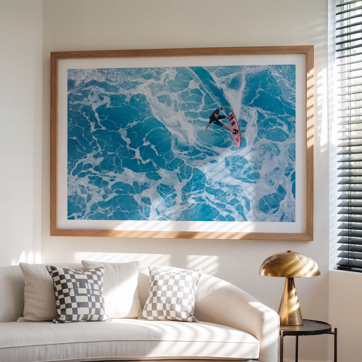 Marble Carve surf photography print with a white border by Sean Davey framed above a sofa beside a lamp