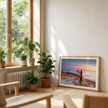 Snow and Sunrise winter surf photography print by Adam Cornick framed and leaning on the floor by a window
