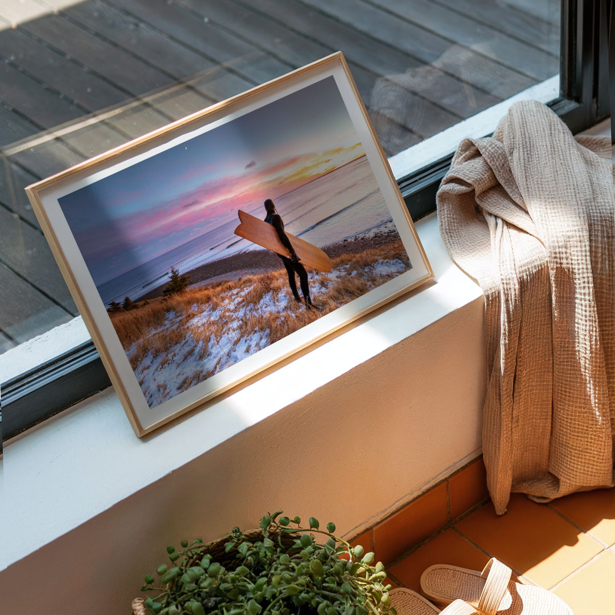 Snow and Sunrise winter surf photography print by Adam Cornick framed on a window ledge