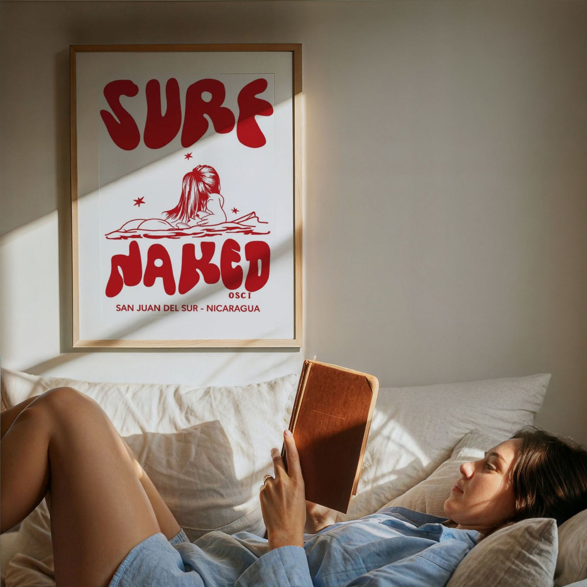 Surf Naked surf illustration print by Osci framed beside someone reading