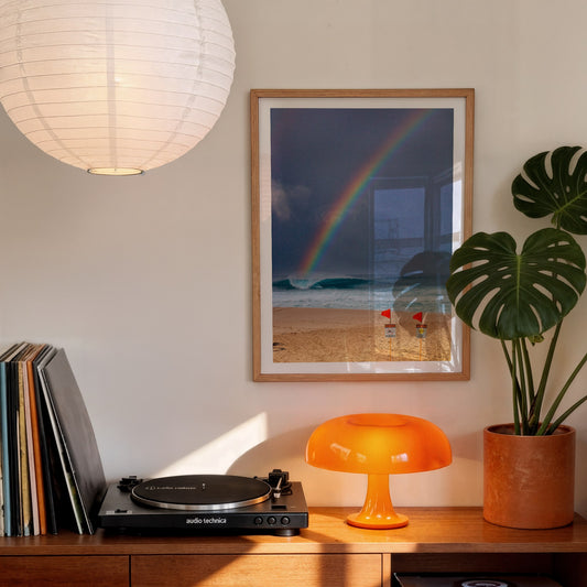 Surfing the Rainbow surf photography print with a white border by Sean Davey framed above a record player and orange lamp